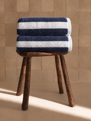 Toallas a rayas azul y blanco sobre un banquito de madera.