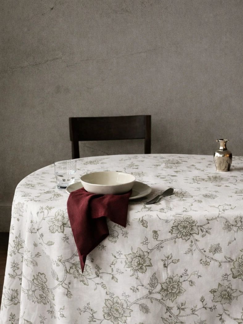 A modest dining setup with a floral tablecloth and dark red napkin.