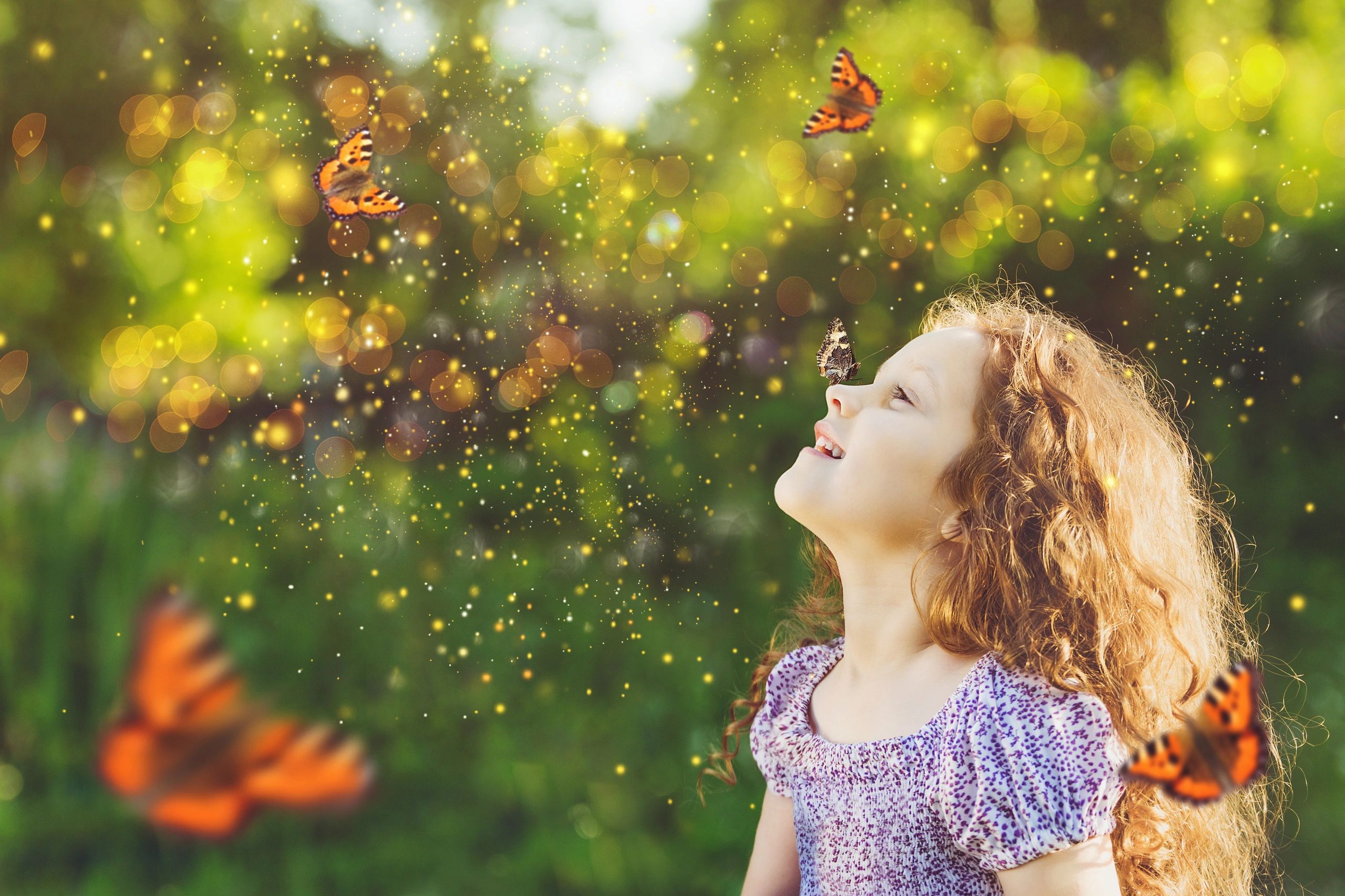 Image of a child smiling at butterflies with sparks of light surrounding her