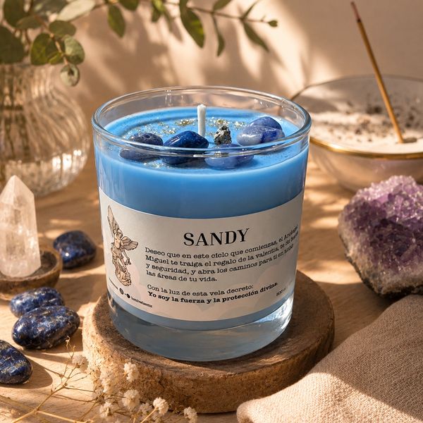 Blue candle with stones and a Spanish message on a wooden surface.