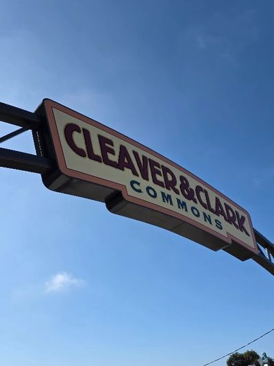 Sign for Cleaver &amp; Clark Commons against a blue sky.