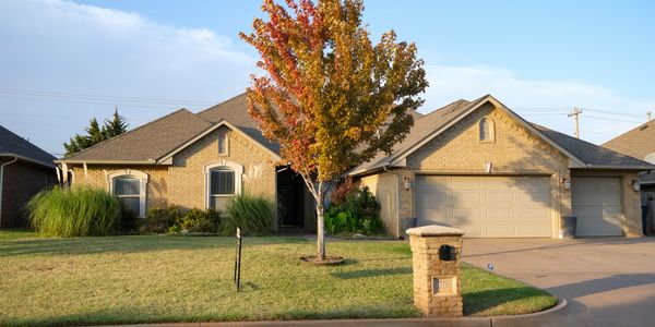 Suburban house with a colorful autumn tree and a large driveway.
