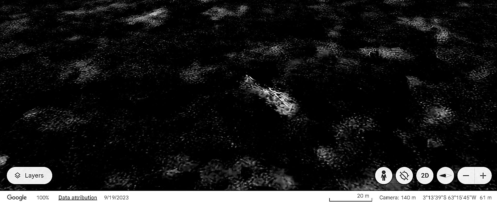 Dark, rocky terrain with scattered light patches, viewed from above.