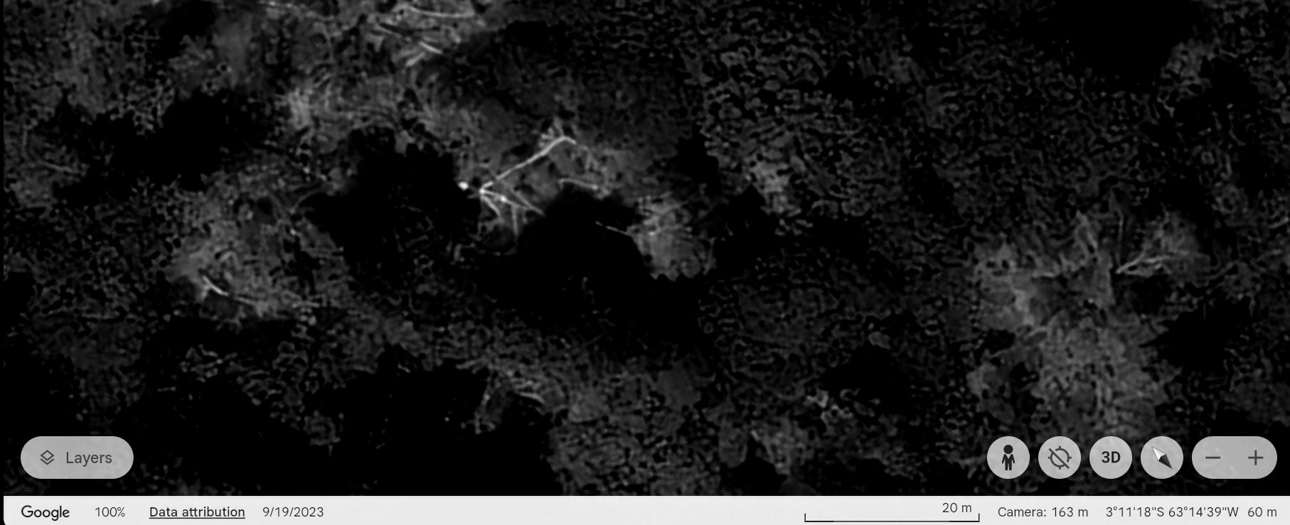 Satellite image of a dark, forested area with some trails or paths visible.