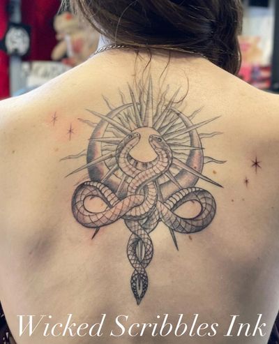 Intricate back tattoo featuring two entwined snakes with a radiant sun and moon.