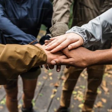 Group of diverse people stacking hands outdoors.
