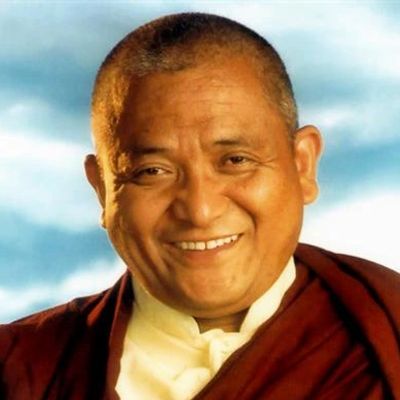 Smiling man with shaved head in traditional attire.