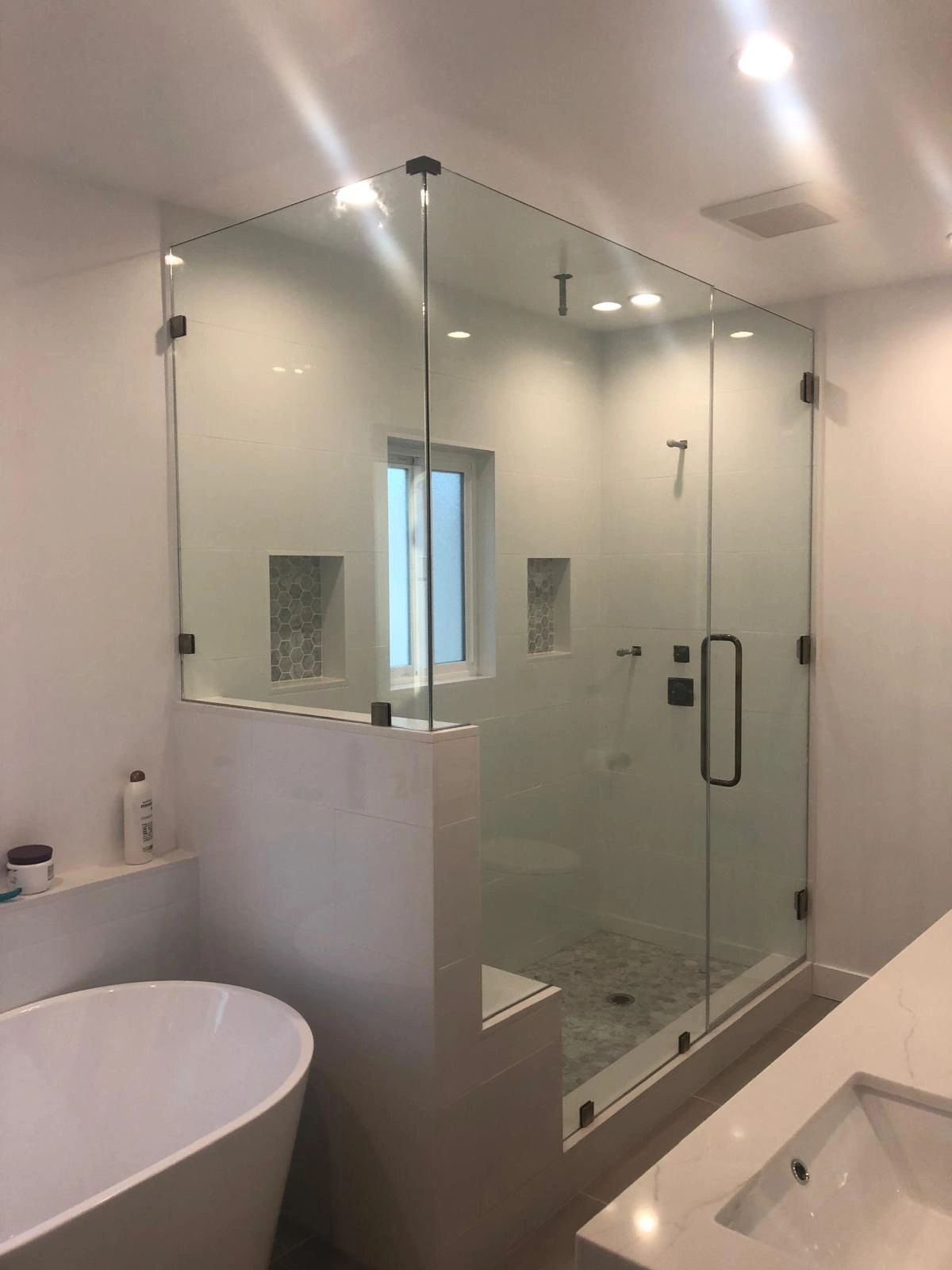 Modern bathroom with glass shower enclosure and freestanding bathtub.