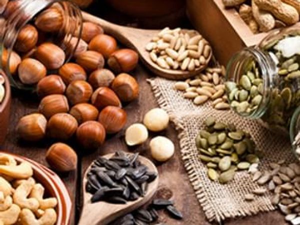 Various nuts and seeds arranged on a rustic wooden surface.