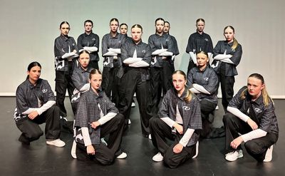 A group of dancers posing in coordinated outfits on stage.