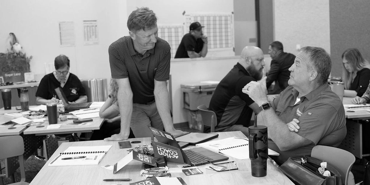 People engaged in a discussion around a table with notebooks and a laptop.