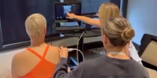 Three women engaged in a medical ultrasound examination.
