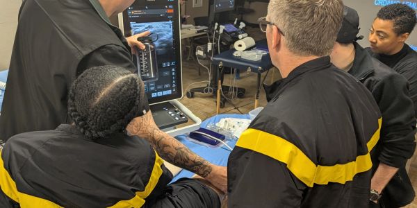 Group of medical professionals examining an ultrasound screen during training.