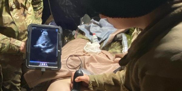 A soldier performs an ultrasound on a patient in a military setting.