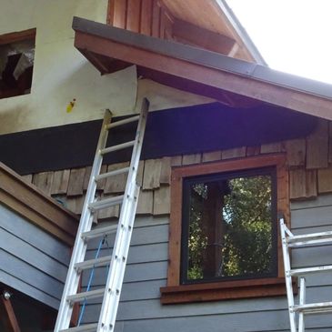 Two ladders leaned against a house under roof repair.