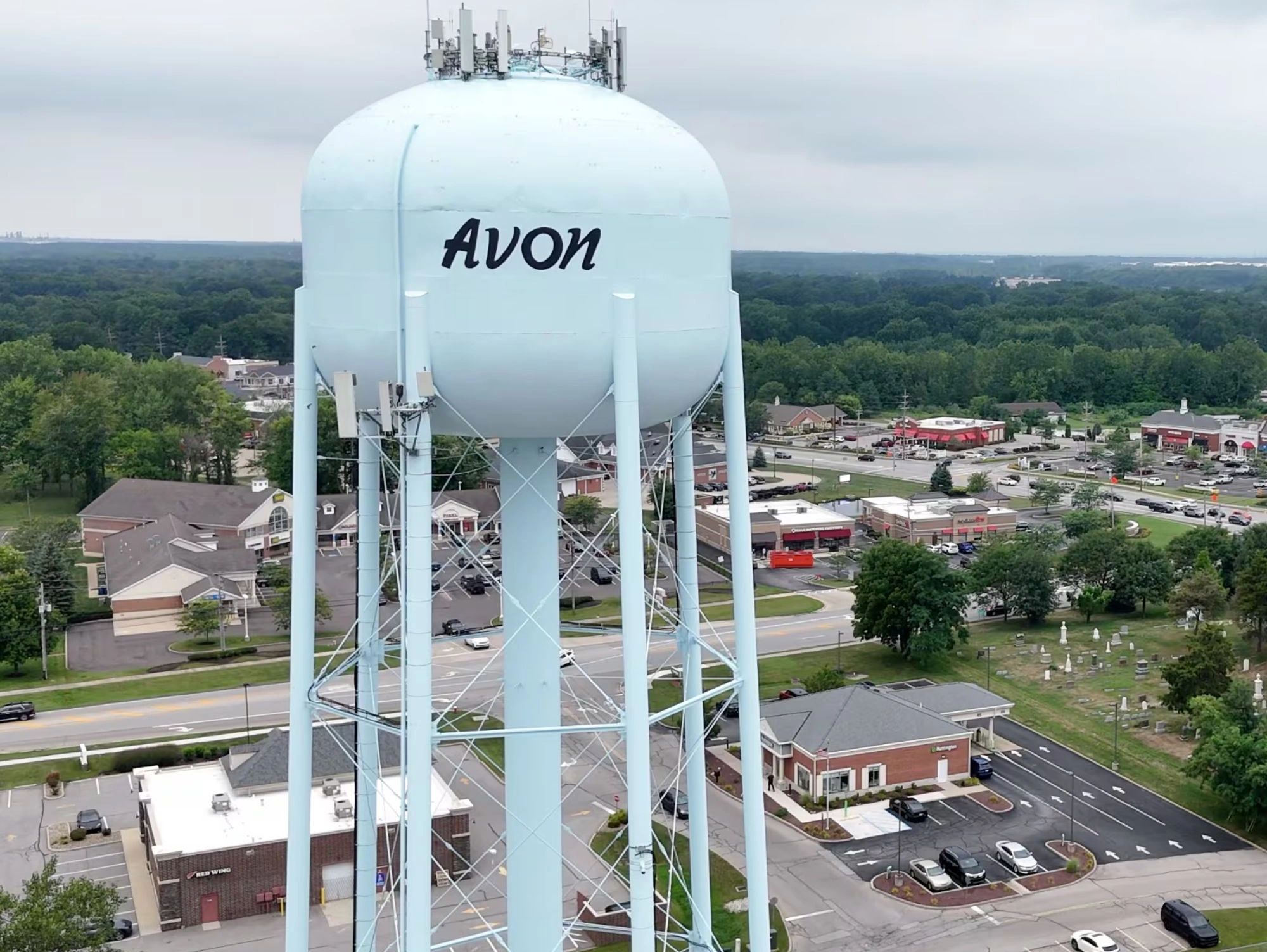 Water tower labeled Avon overlooking a suburban area with shops and roads.