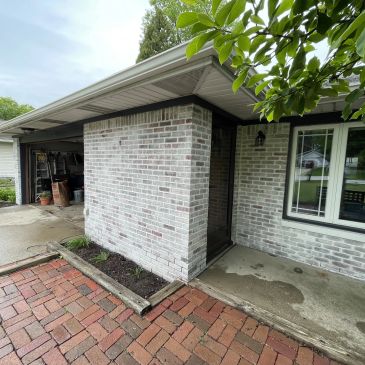 Front porch and entrance of a brick house with a small garden bed and a driveway.