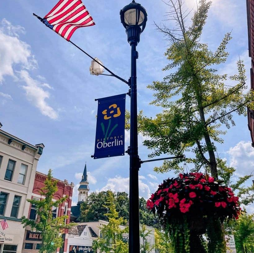 Street scene in historic Oberlin with American flag and blooming flowers.