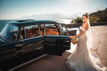Eine Braut mit einem Oldtimer am Meer