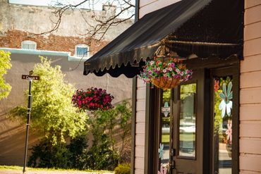 Colorful hanging flower baskets brighten the outdoor shop entrance.