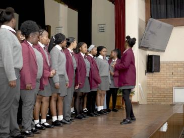 Students lined up on stage, listening to a teacher.