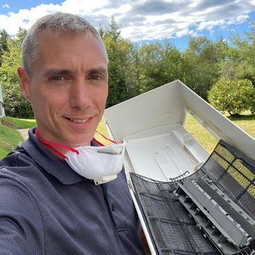 performing a professional heat pump deep clean — spraying cleaning solution on mini-split coils, 