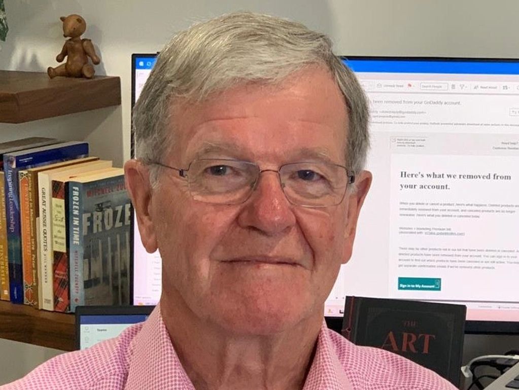 Older man with glasses in front of a computer screen.