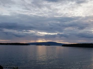 Calm water under a cloudy sky during sunset.