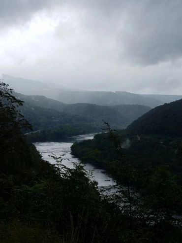 Cloudy sky over a river in a mountainous area.