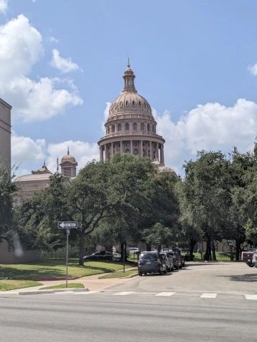 State Capitol building with trees and a street in front.