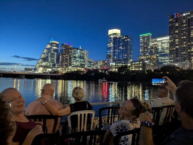 People enjoying a nighttime city skyline from a waterfront.