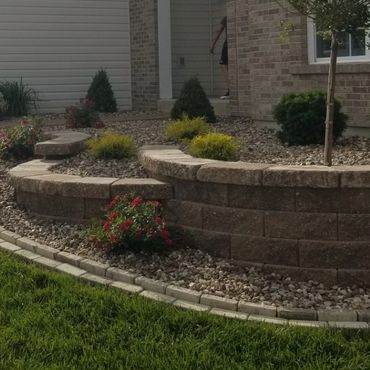 Stone retaining wall with plants and landscaping.