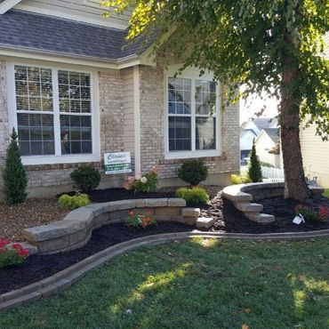 Front yard landscaping with retaining walls and plants.