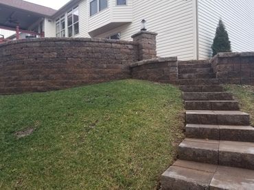 Stone steps from paver patio and retaining wall to accentuate the natural slope and provide safe acc