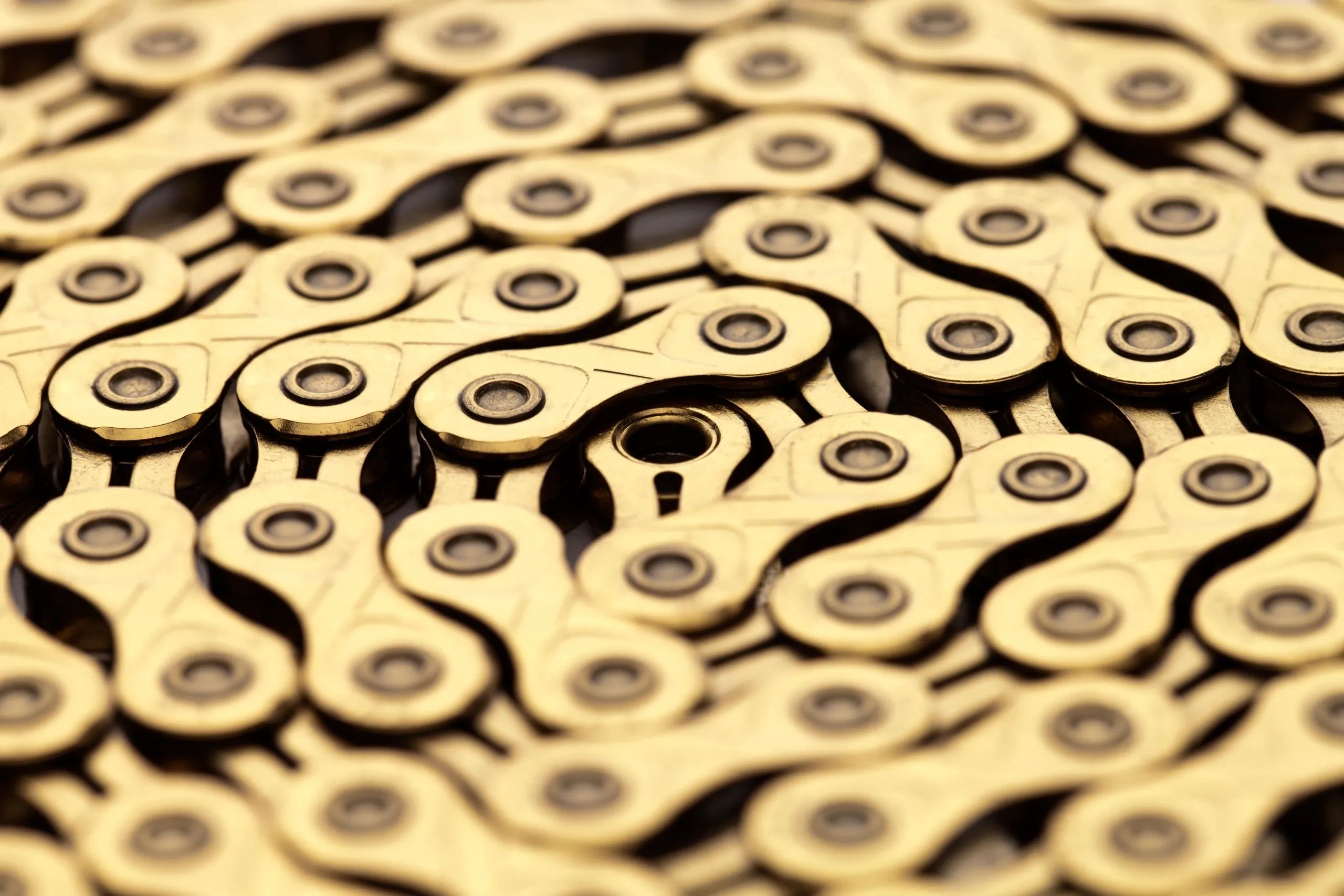 Close-up of a golden bike chain with intricate links and pins.
