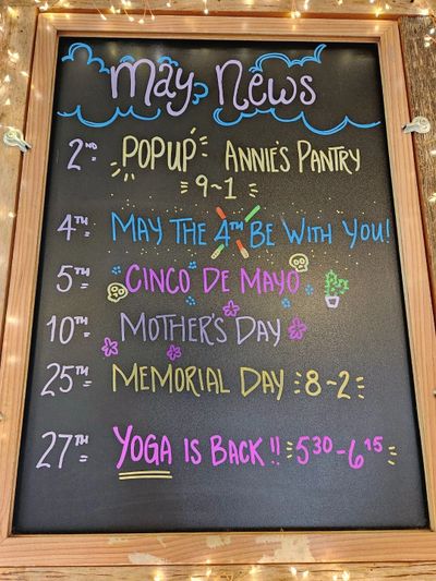 Chalkboard with colorful May event announcements and dates.