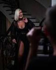 Woman in a black dress posing for a photo indoors.