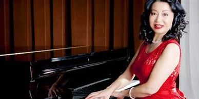 Woman in a red dress playing a grand piano.