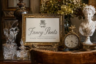 Elegant estate sale display with vintage items and a framed sign.