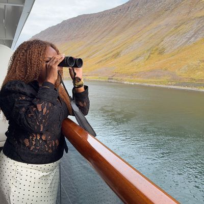Woman on a boat using binoculars to look at the landscape.