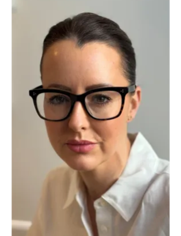 Woman wearing black glasses and white shirt.
