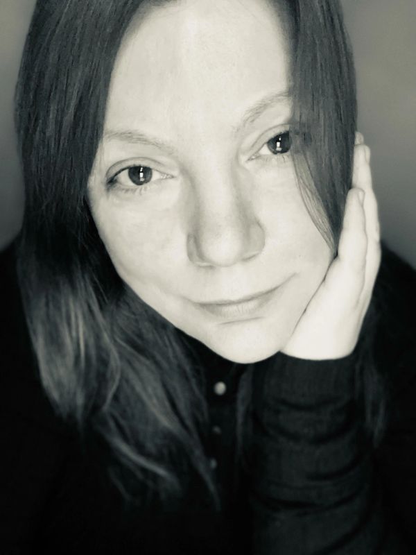 Close-up black and white portrait of a woman resting her face on her hand.