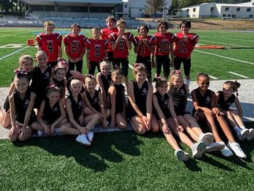 Youth football and cheerleading teams pose on field.