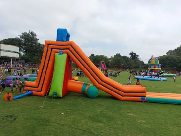 High orange inflatable water slide with pool at the end