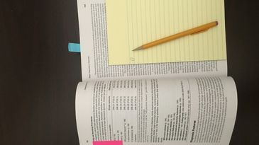 Open book with notes and pencil on a desk.