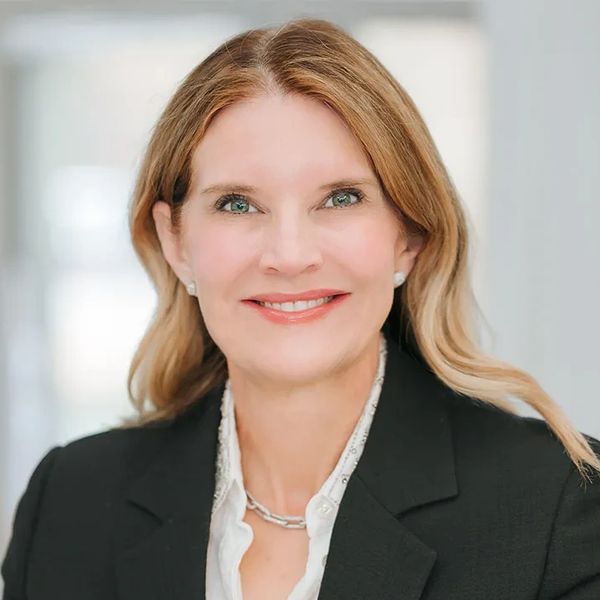 Professional woman smiling, wearing a black blazer and white shirt.