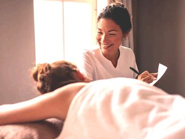 A massage therapist shares insights while smiling with a client.