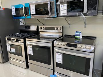 A selection of stainless steel ovens and microwaves displayed in a store.