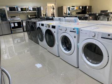 Row of washing machines and dryers in a home appliance store.