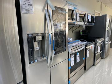 Row of stainless steel kitchen appliances in a showroom.